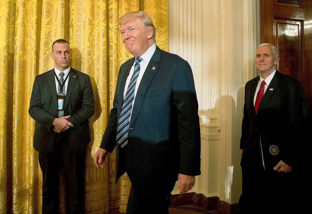 President Donald Trump, center, accompanied by Vice President Mike Pence, right, arrives for a White House senior staff swearing in ceremony in the East Room of the White House, Sunday, Jan. 22, 2017, in Washington. (AP Photo/Andrew Harnik)